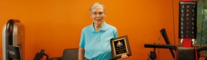 a woman in a blue shirt is holding a plaque that says ' alzheimer ' on it