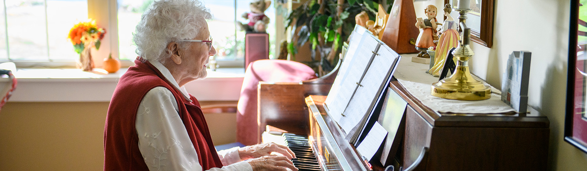 an elderly woman in a red vest is playing a piano