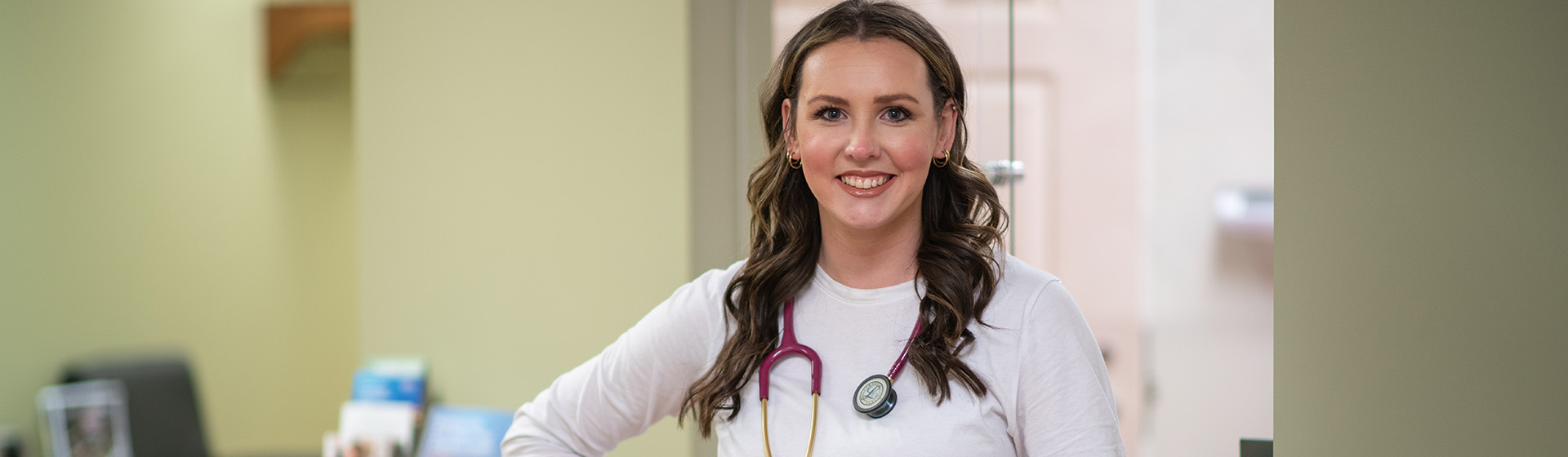 a woman with a stethoscope around her neck smiles for the camera