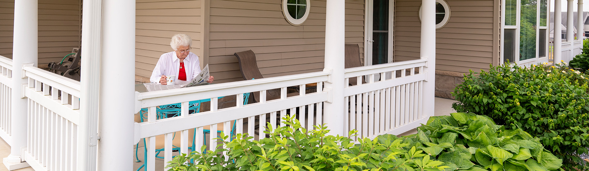 a woman sits on a porch reading a newspaper